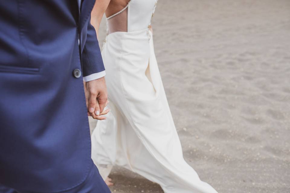detalle de una pareja caminando por la arena