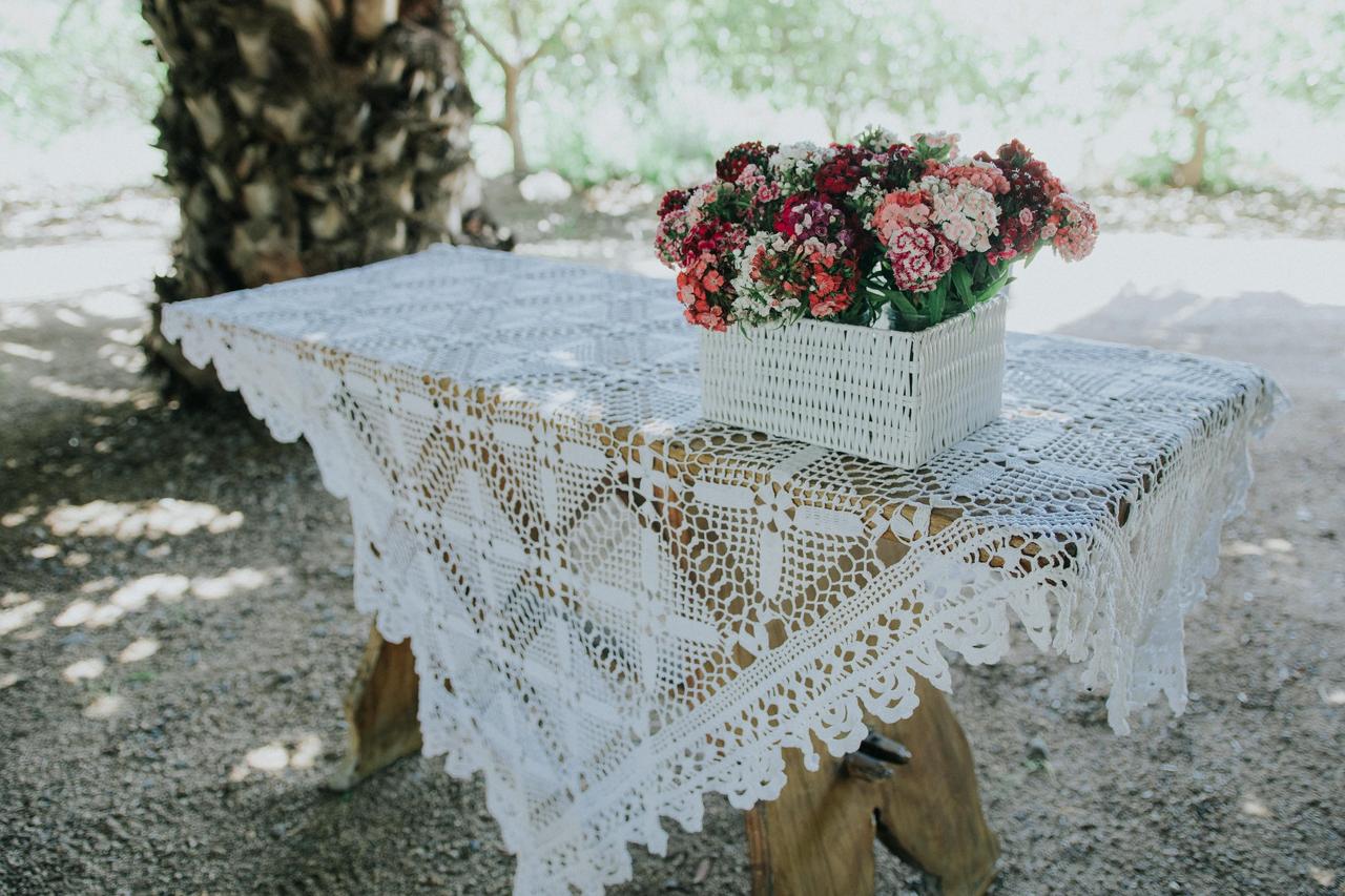 mesa con mantel tejido y caja con flores