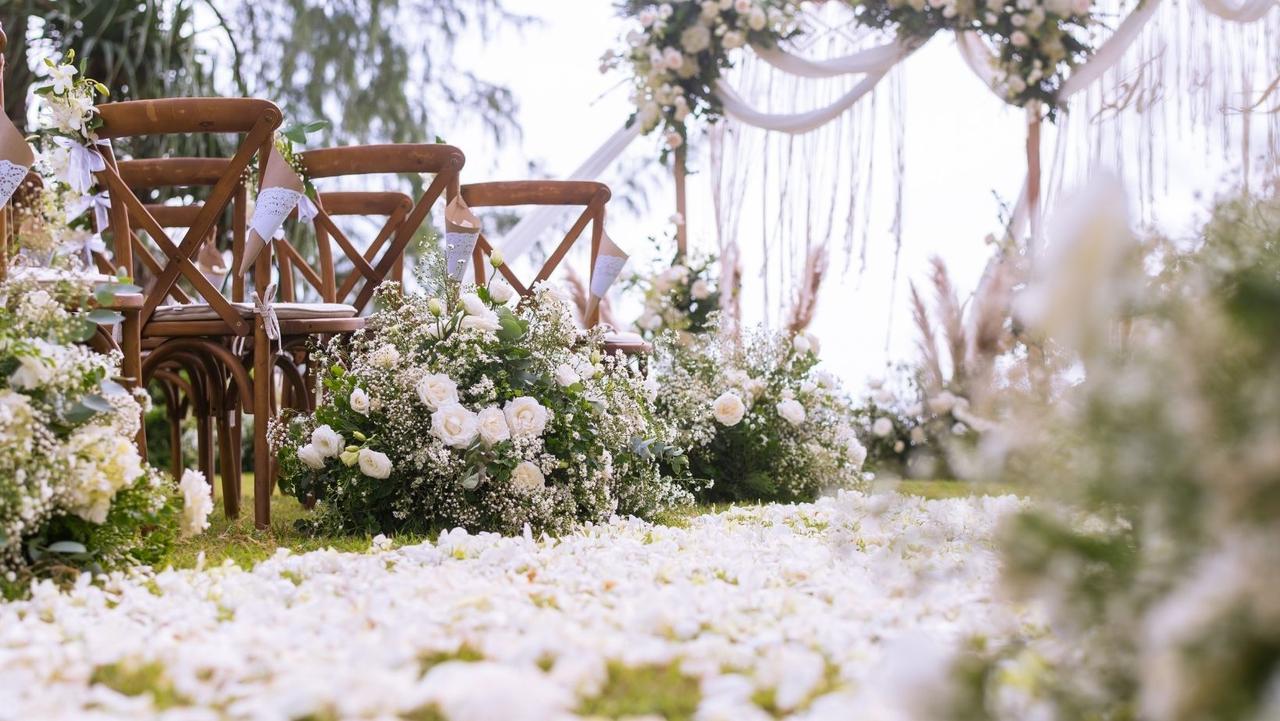 pétalos blancos en el pasto y sillas de madera