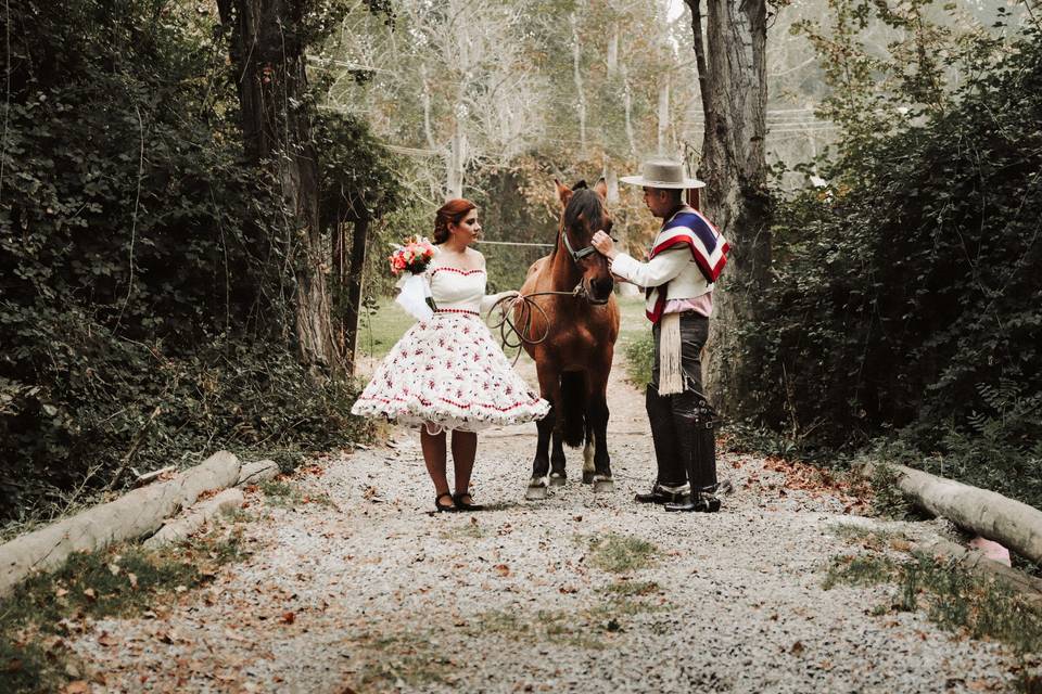 pareja vestida de huasos junto a un caballo