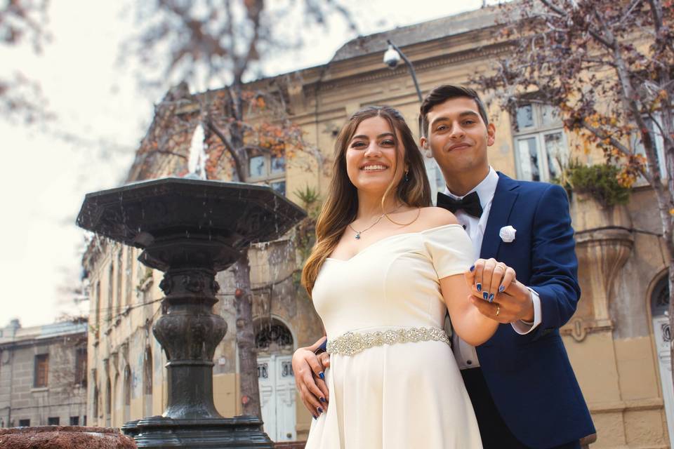 Pareja tomada de la mano frente a una fuente