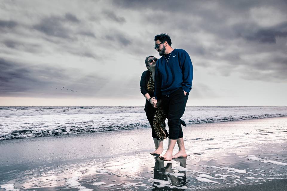 Novios caminando por la playa descalzos