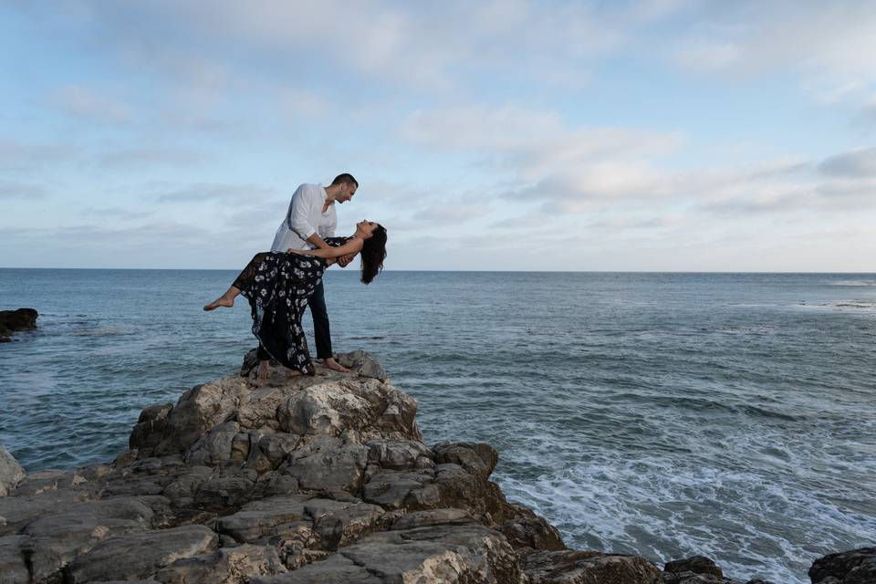 Novios posando en unas piedras frente al mar