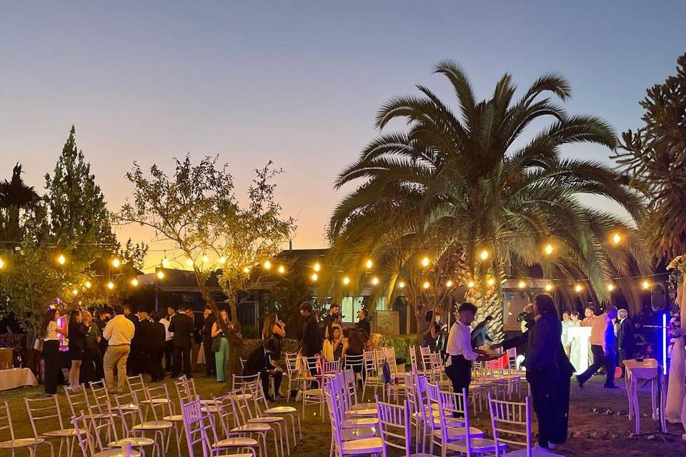 Jardín con sillas blancas y luces