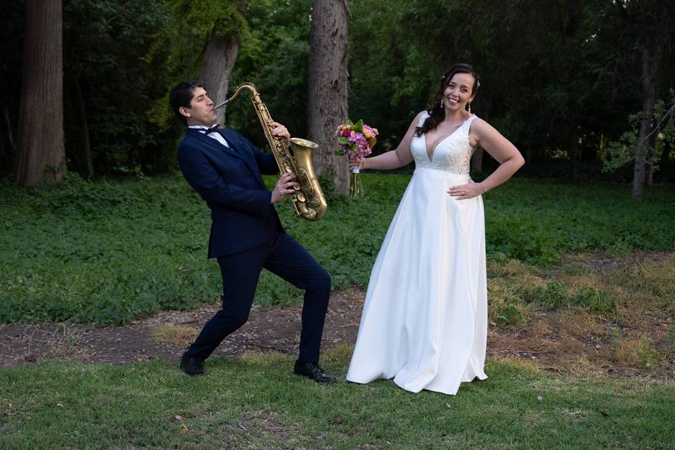 Saxofonista y novia en enfrente de los árboles