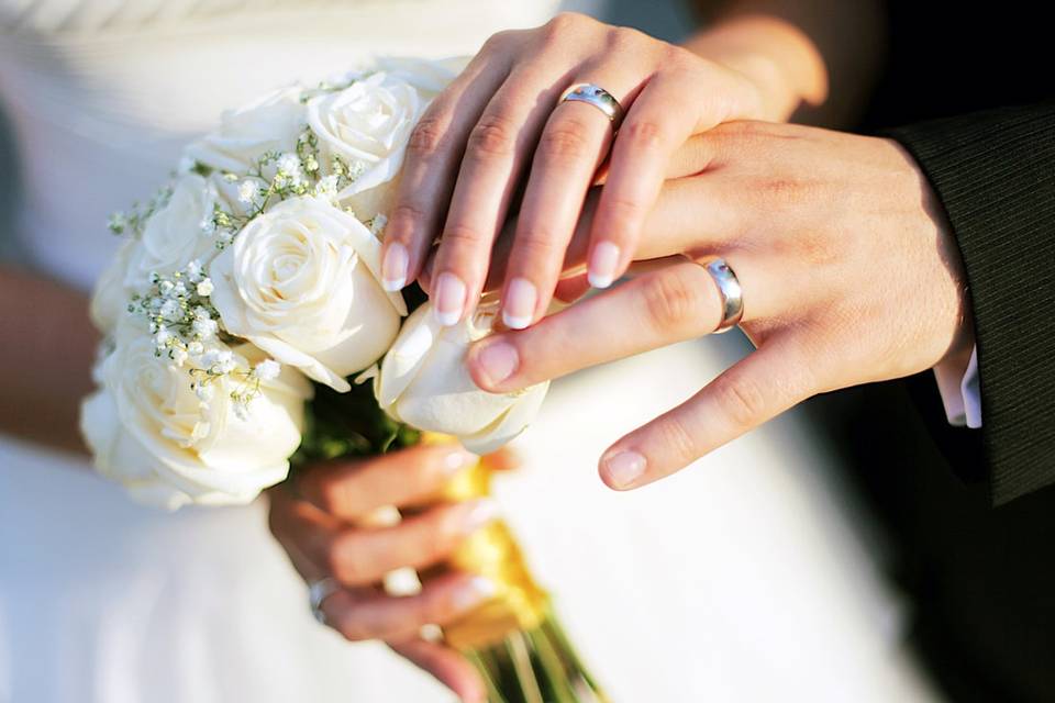 Tomados de la mano con un ramo de flores blancas