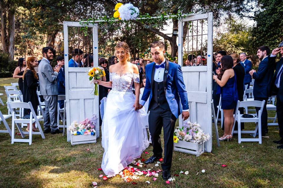 Novios entrando por una puerta blanca al jardín