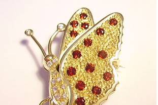 Prendedor de oro con brillantes rojos y forma de mariposa