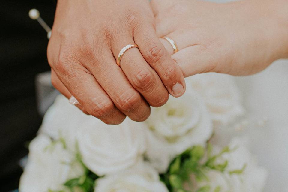 Tommándose de la mano y enseñando los anillos de boda