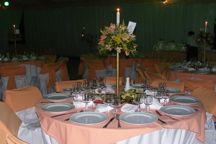 Mesa con mantel rosa y arreglo floral con vela