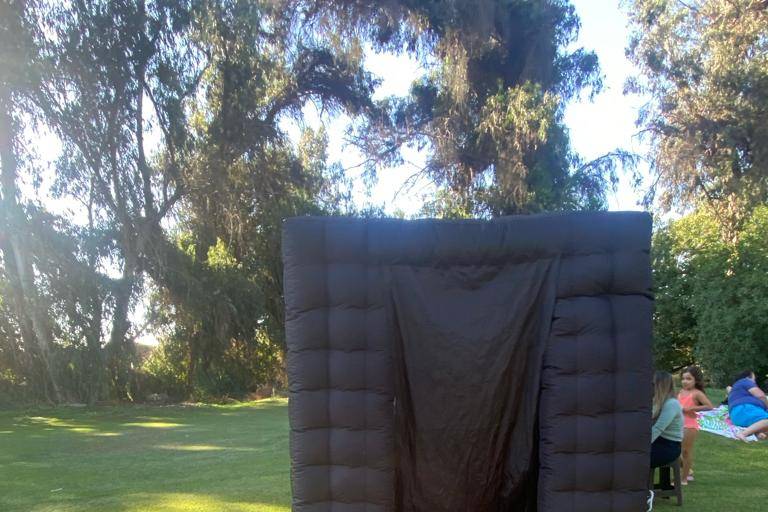 Cabina de foto negra con alfombra roja en el jardín